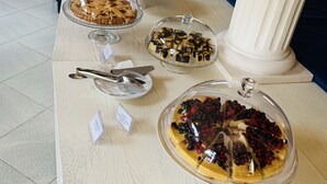 A buffet table with various desserts under glass covers, a knife on a plate, and a sign indicating a special offer. - Hotel Deanna Golf (Cervia)