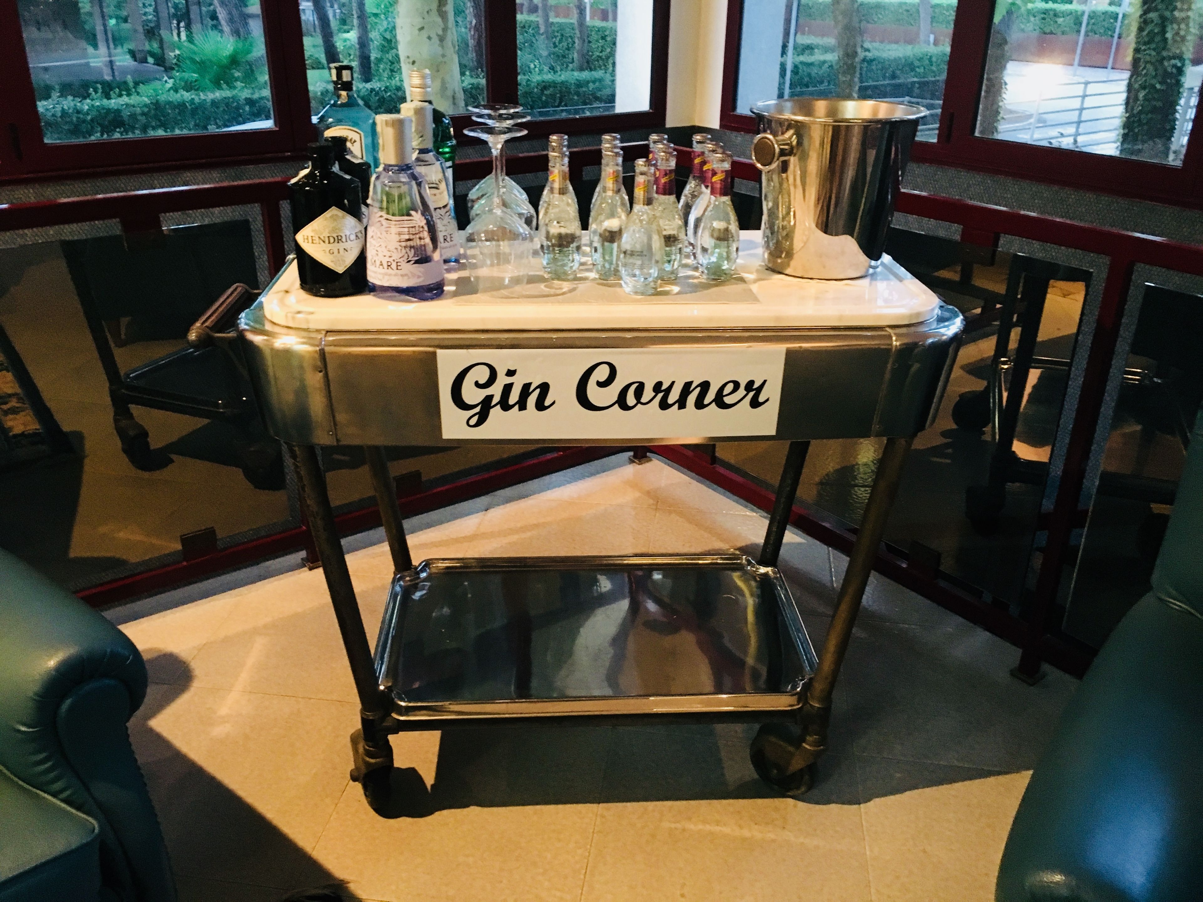 A cart labeled "Gin Corner" with various bottles of gin and a large metal container.