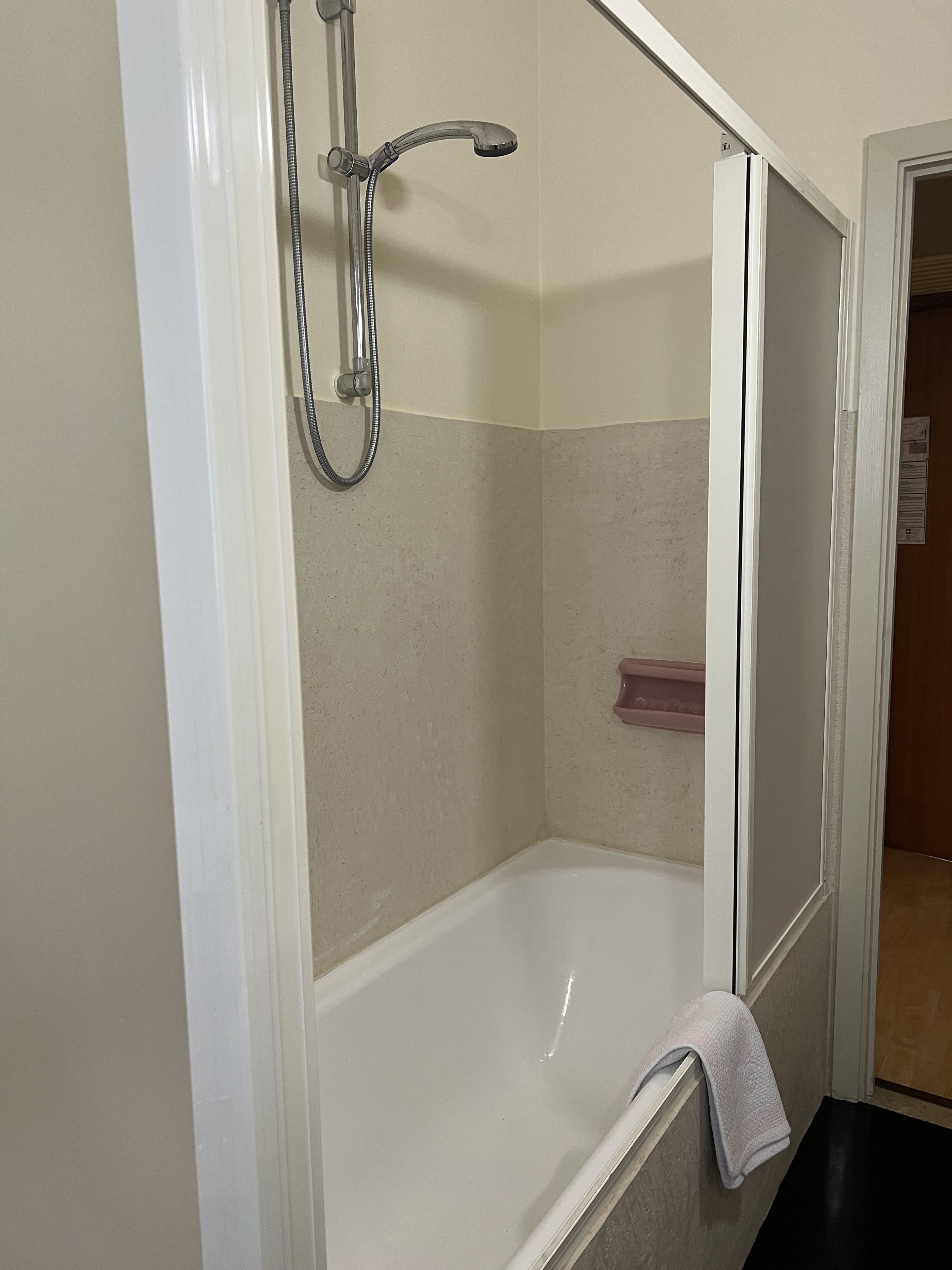 A bathroom with a shower, a bathtub, and a towel rack.