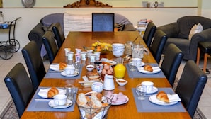 Comedor con una larga mesa de madera dispuesta para el desayuno, rodeada de sillas.