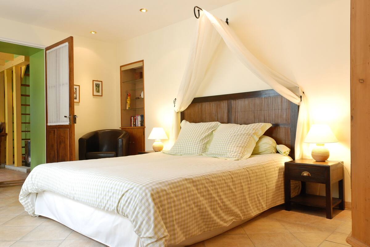 A bedroom with a large bed, a nightstand with a lamp, and a wooden headboard.