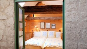 Un dormitorio acogedor con techo de madera y ventana con marco verde.