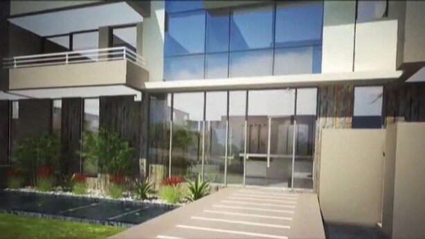Un edificio moderno con amplios ventanales, techo plano y un área ajardinada con plantas y un sendero.