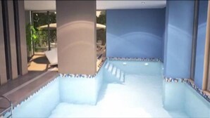 Una piscina interior moderna con paredes de vidrio transparente, piso de baldosas y un diseño sencillo y limpio.