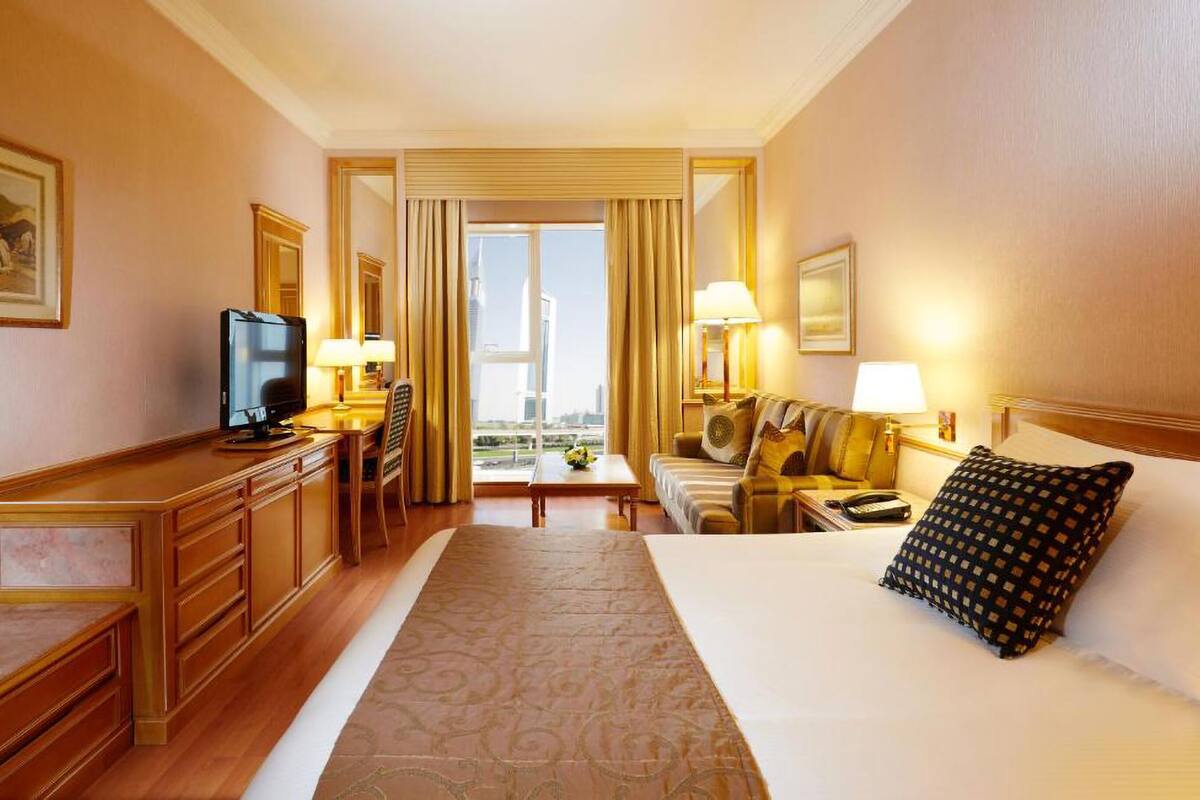 Ein Hotelzimmer mit Bett, Fernseher, Schreibtisch und Blick auf die Stadt.