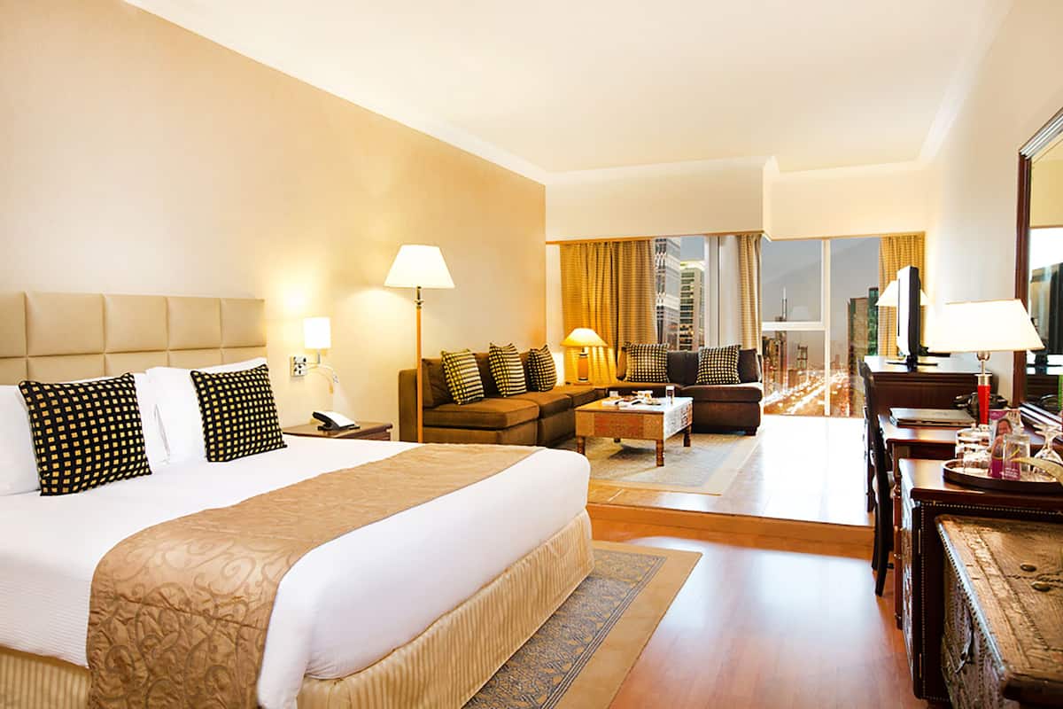 Ein Hotelzimmer mit einem großen Bett, einer Schlafcouch, einem Couchtisch und einem Fernseher.