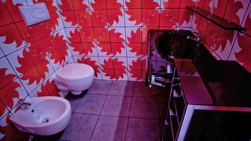 A bathroom with red maple leaf patterned tiles, a white toilet, and a bidet.