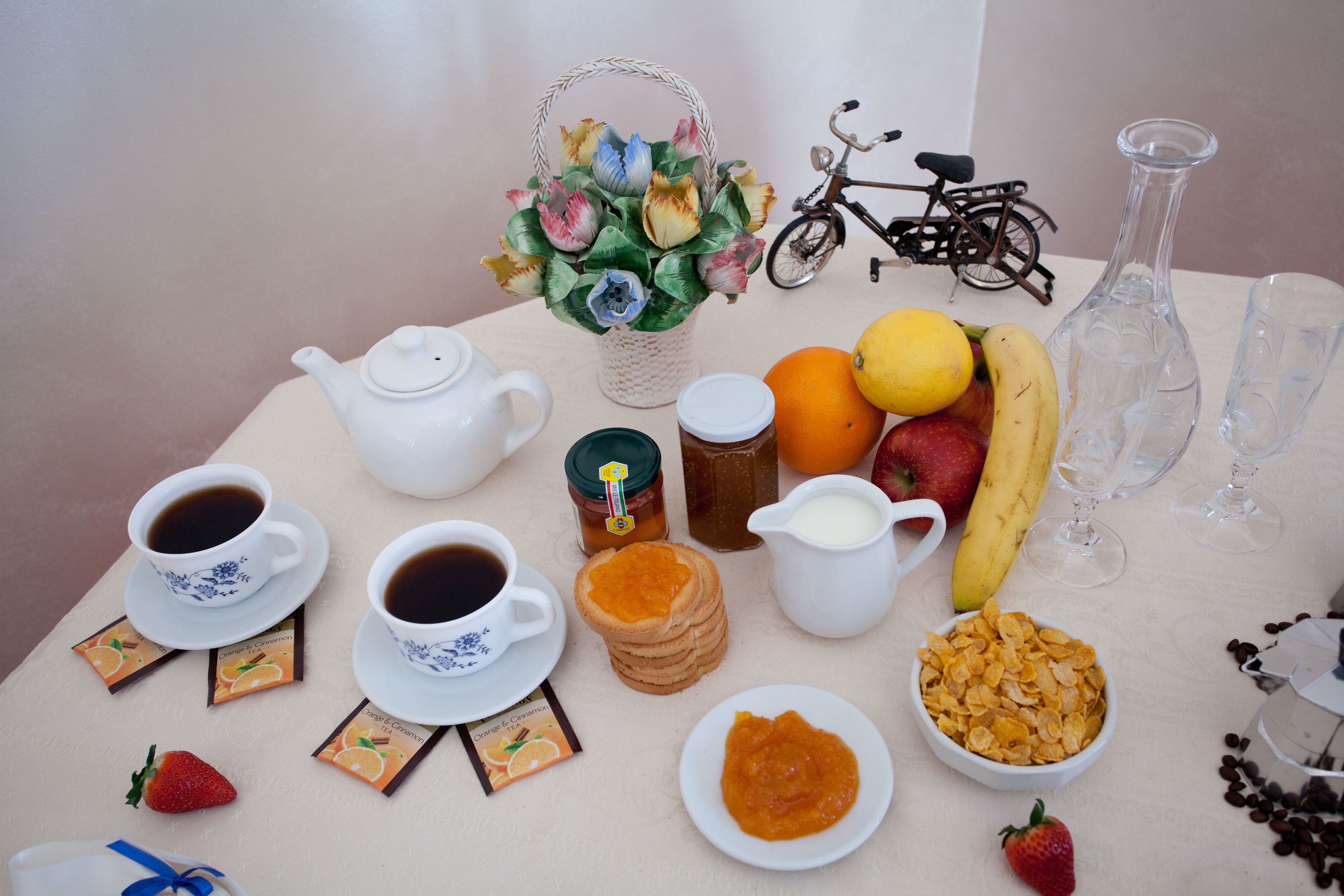Ein Tisch mit Frühstücksangeboten, darunter Tee, Kaffee, Obst und Müsli.