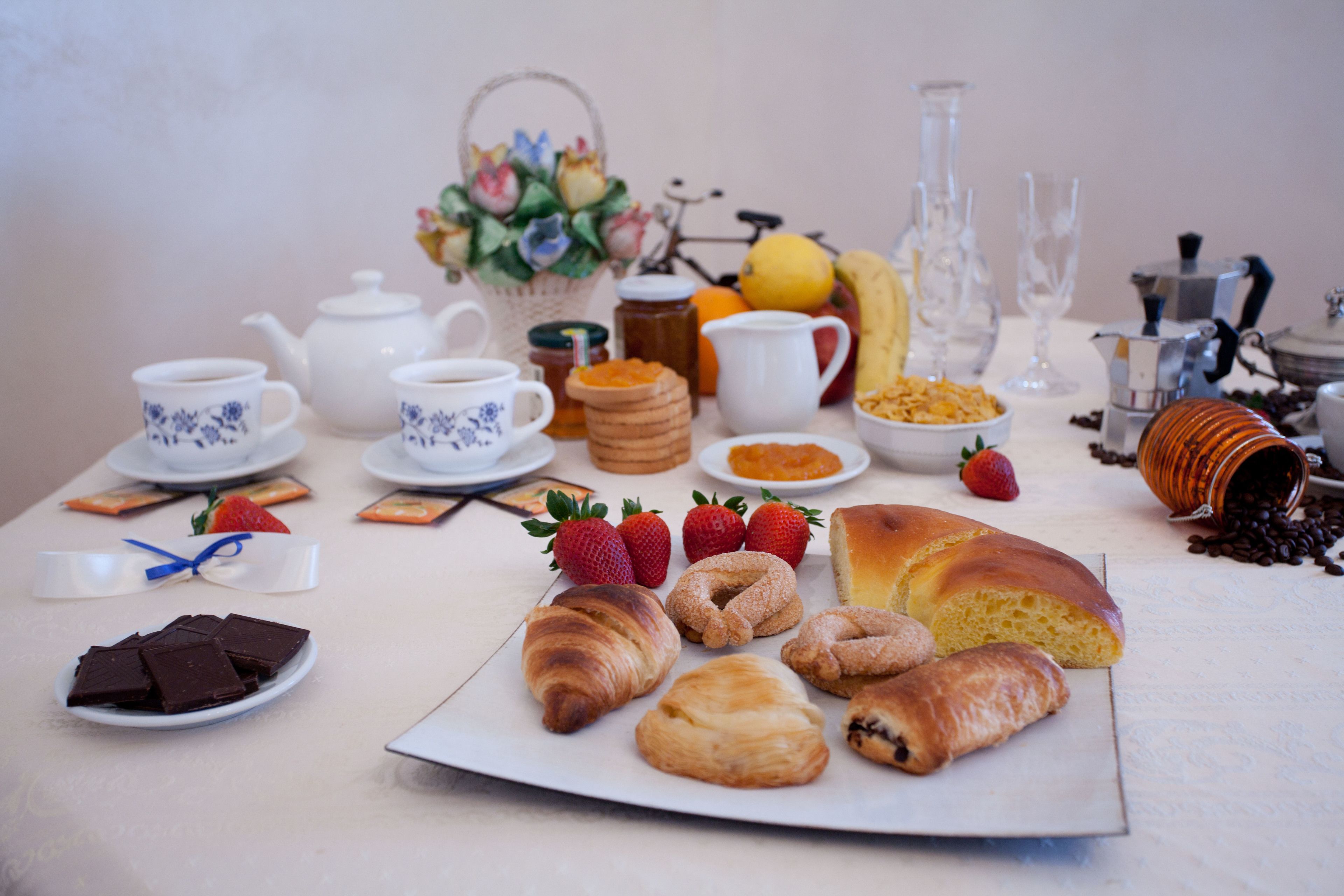 A breakfast table with pastries, fruits, and coffee-making equipment.