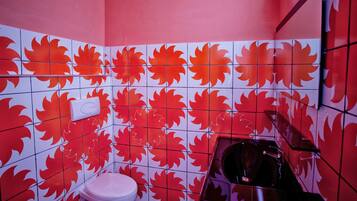 Et badeværelse med røde ahornblad-fliser, et hvidt toilet og en vask.