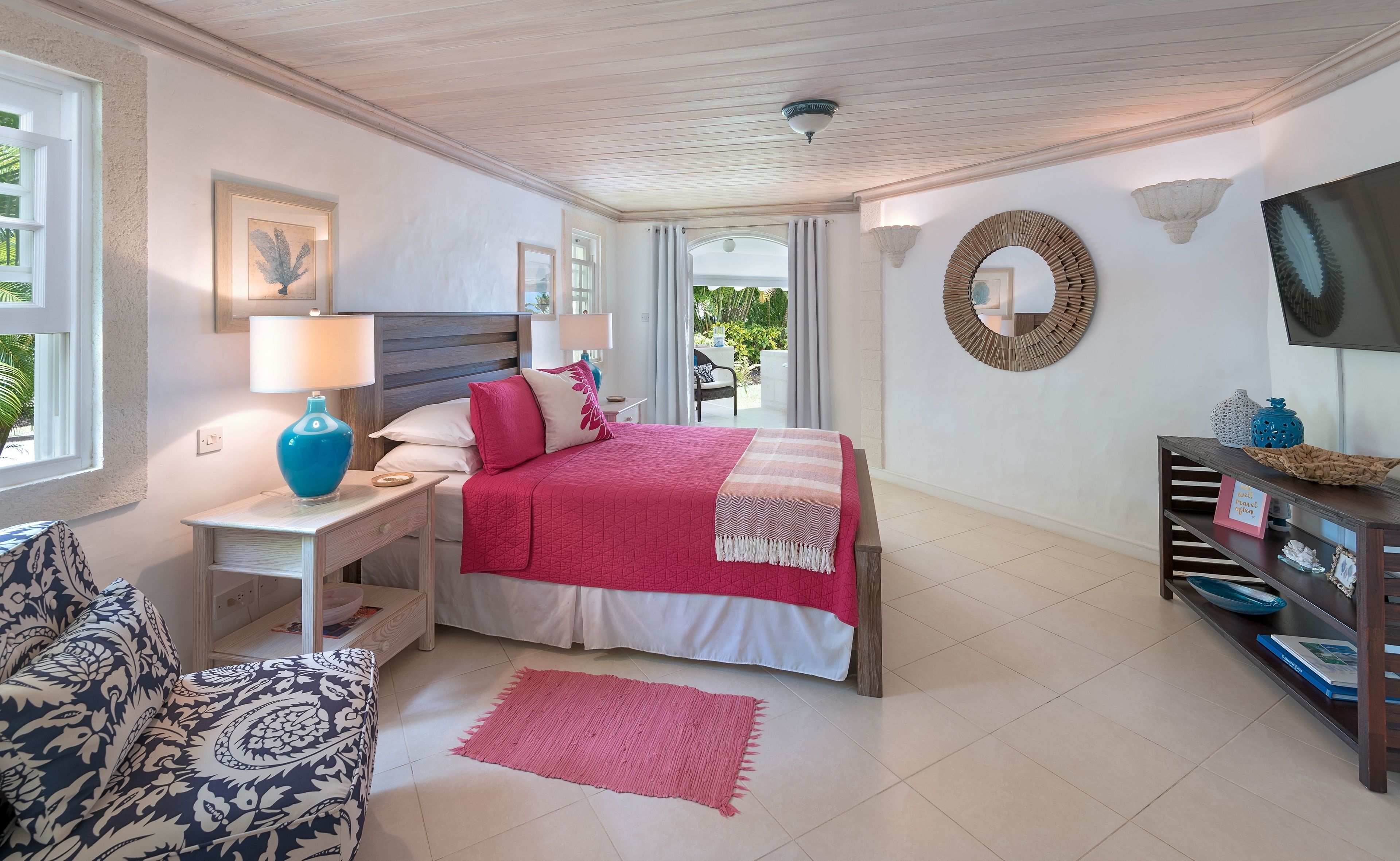 A bedroom with a bed, bedside tables, a TV, and a view of the outdoors.