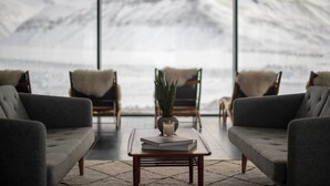 A cozy seating area with a view of snow-covered mountains through large windows. - Eleven Deplar Farm - All inclusive (Skagafjörour)