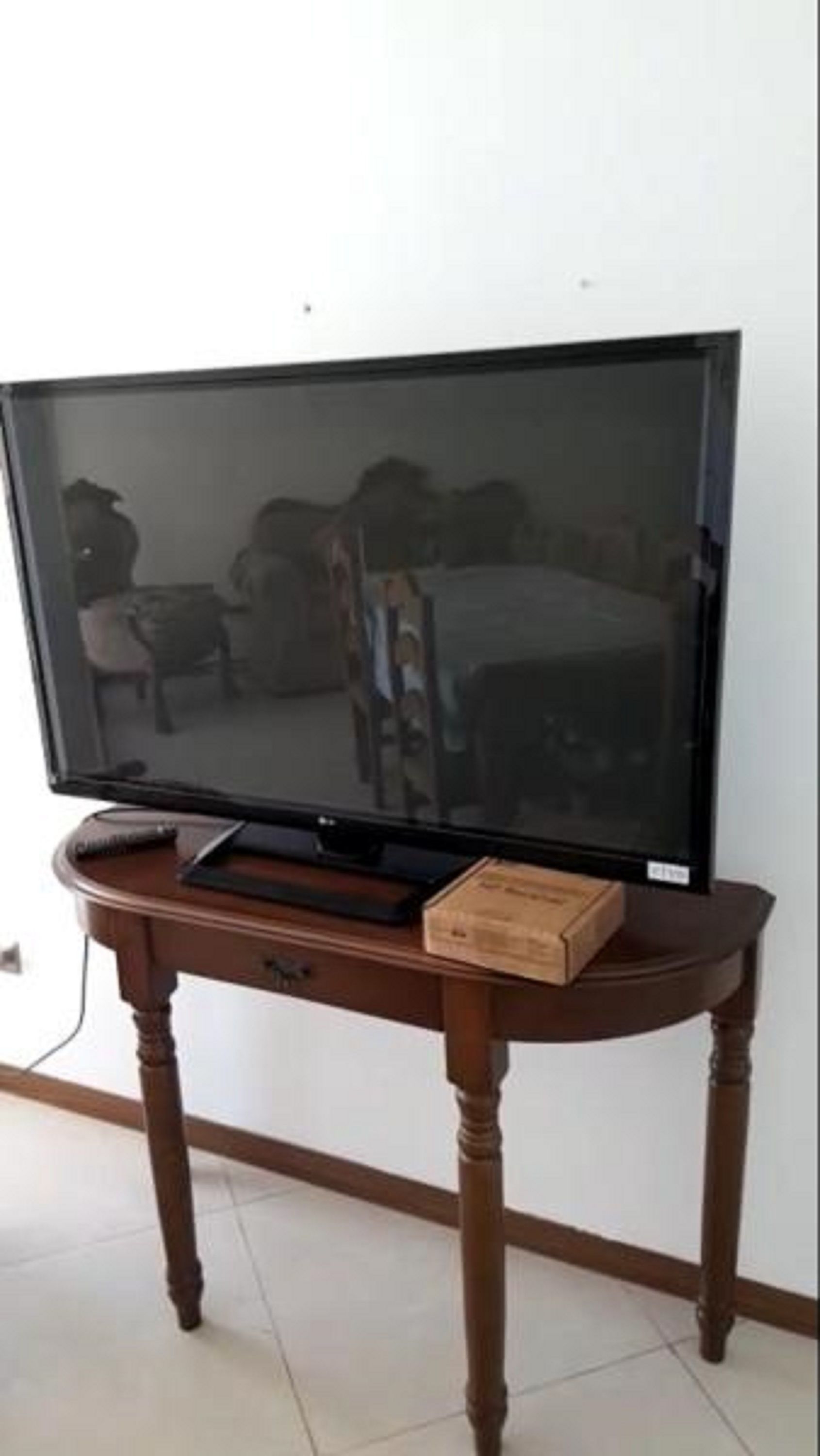 A television on a wooden table against a white wall.