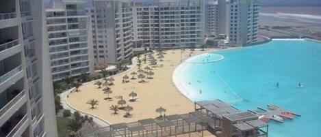 Un resort con una piscina grande, zona de playa y edificios altos.