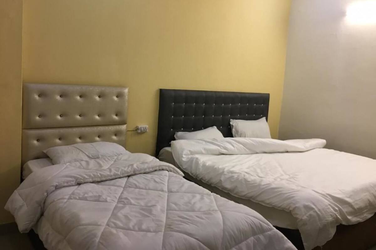 Two beds with headboards, a wall socket, and a light fixture.