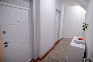 A hallway with white doors, a small table with a vase of flowers, and a carpeted floor. - Central Spot Apartments (Belgrade)