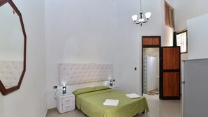 A bedroom with a bed, nightstands, a mirror, and a wardrobe. - Hostal Belvédère (Havana)