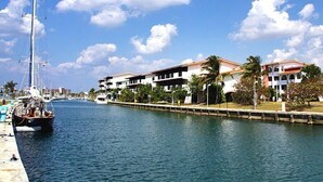 A canal with a sailboat docked on the left, lined with buildings and palm trees. - Hostal Belvédère (Havana)