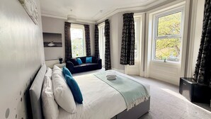 A bedroom with a bed, a sofa, and a window with curtains. - The Hedley Townhouse (Bournemouth)