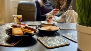 A room with a table set for two, featuring a coffee mug, biscuits, and a plant. - The Hedley Townhouse (Bournemouth)