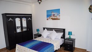 Un dormitorio con cama, mesitas de noche, un armario y un cuadro en la pared.