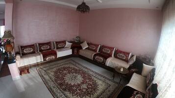 A living room with a sofa set, a patterned rug, and a ceiling fan.