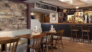 A bar area with wooden furniture, stone walls, and a menu board.