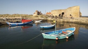 A harbor with several boats docked near a historic stone building.