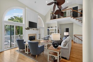 A spacious living area with a fireplace, seating, and a staircase leading to an upper level.