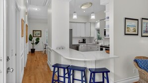 Una cocina moderna con armarios blancos, encimera de mármol y taburetes de bar azules.