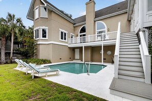 A two-story house with a swimming pool, a balcony, and a staircase leading to the upper floor.
