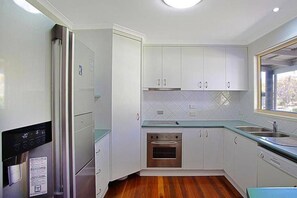 A modern kitchen with white cabinets, a stainless steel oven, and a built-in dishwasher.