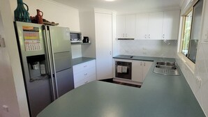 Cocina compacta con refrigerador, microondas, horno y lavaplatos.