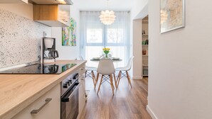 A modern kitchen with a wooden countertop, a coffee machine, and a dining area with a white table and chairs.