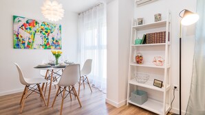 A dining area with a white table, four chairs, and a colorful abstract painting on the wall.
