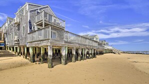 A wooden pier extending from a beachfront building with multiple levels and balconies. - Harbor Views + Private Deck: Waterfront P-Town Apt (Provincetown)