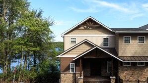 A two-story house with a stone foundation, a wooden porch, and a view of a lake. - DRAMATIC LAKEFRONT EAGLES LANDING BREATHTAKING VIEWS (Lake Harmony)
