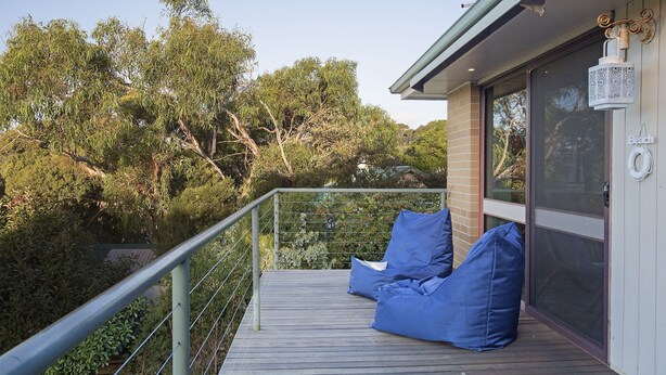 A balcony with blue bean bags, a metal railing, and a view of trees. - ROANJOKA - DROMANA.... (Dromana)
