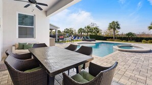 Eine überdachte Terrasse mit Pool, Gartenmöbeln und Deckenventilator.