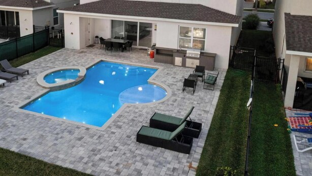 Ein Garten mit Swimmingpool, Liegestühlen und Grillplatz.