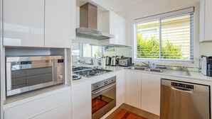 A modern kitchen with stainless steel appliances, a built-in oven, and a window with a view of greenery.
