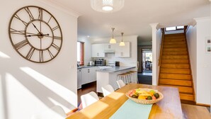 A modern kitchen with white cabinets, a central island, and a dining area with a wooden table and chairs.