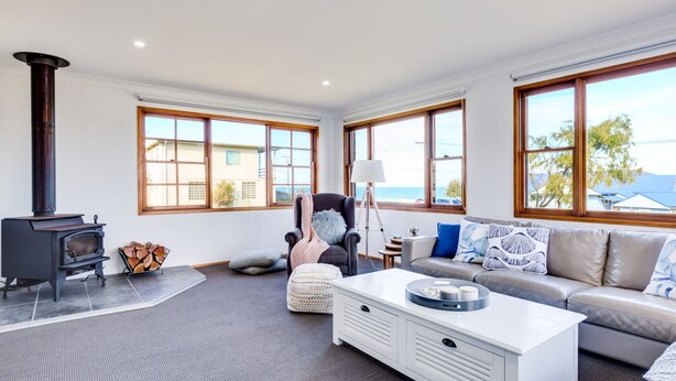 A spacious living room with a fireplace, large windows, a sofa, and a coffee table.