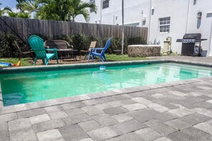 Relax by the pool surrounded by a patio area and lawn chairs.