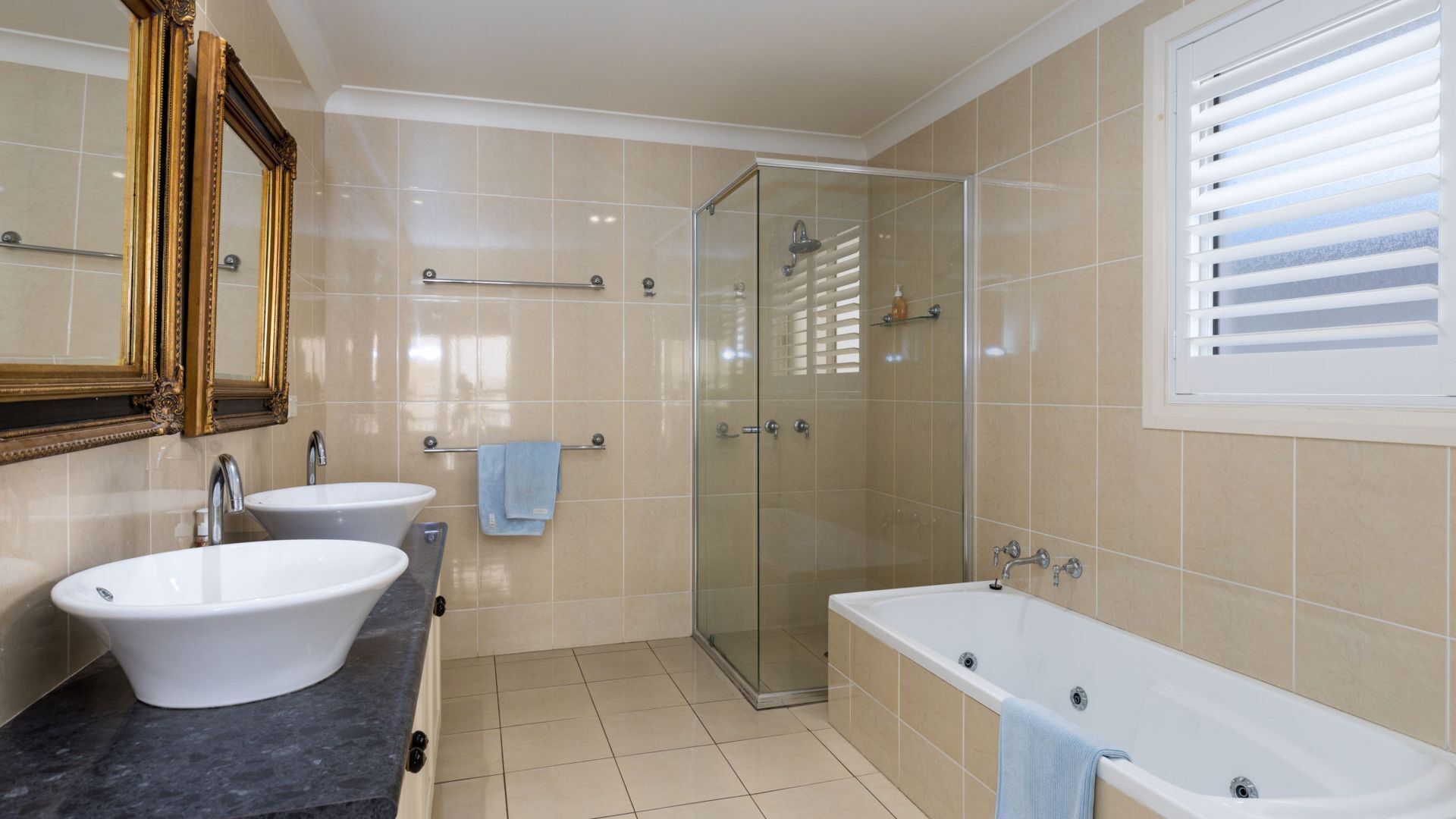 Un baño moderno con un espejo grande, dos lavabos, ducha y bañera.