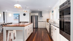 A modern kitchen with white cabinetry, stainless steel appliances, and a wooden island. - Mistral, Gerroa, South Coast (Gerroa)