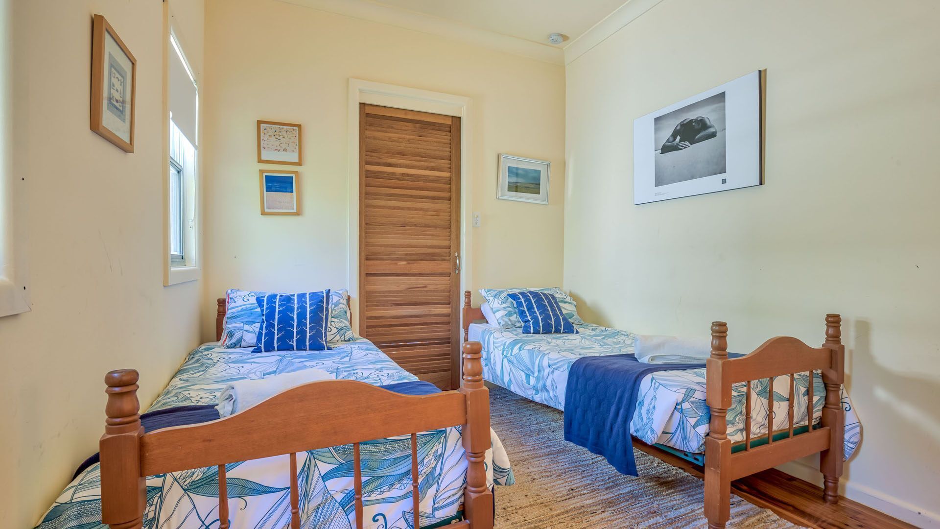 A bedroom with two wooden beds, a wooden wardrobe, and a framed picture on the wall.