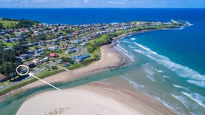 Vue aérienne d’une zone résidentielle côtière, avec des maisons, une plage et l’océan.