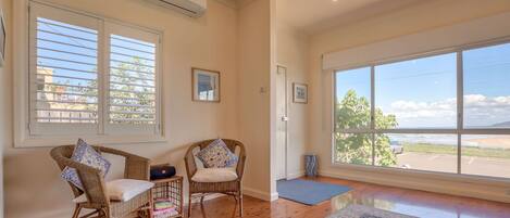 A spacious room with large windows, wicker chairs, a small rug, and a door leading outside.