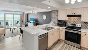 A modern kitchen with a large island, stainless steel appliances, and a view to the outside.